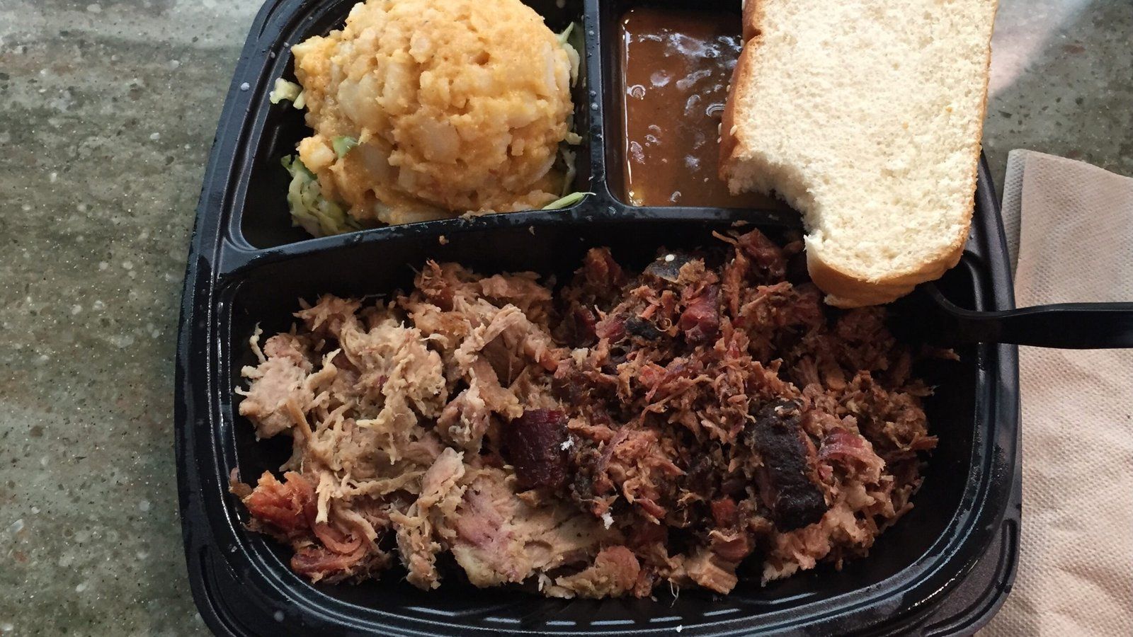 Plate of pulled pork barbecue with mac and cheese and bread