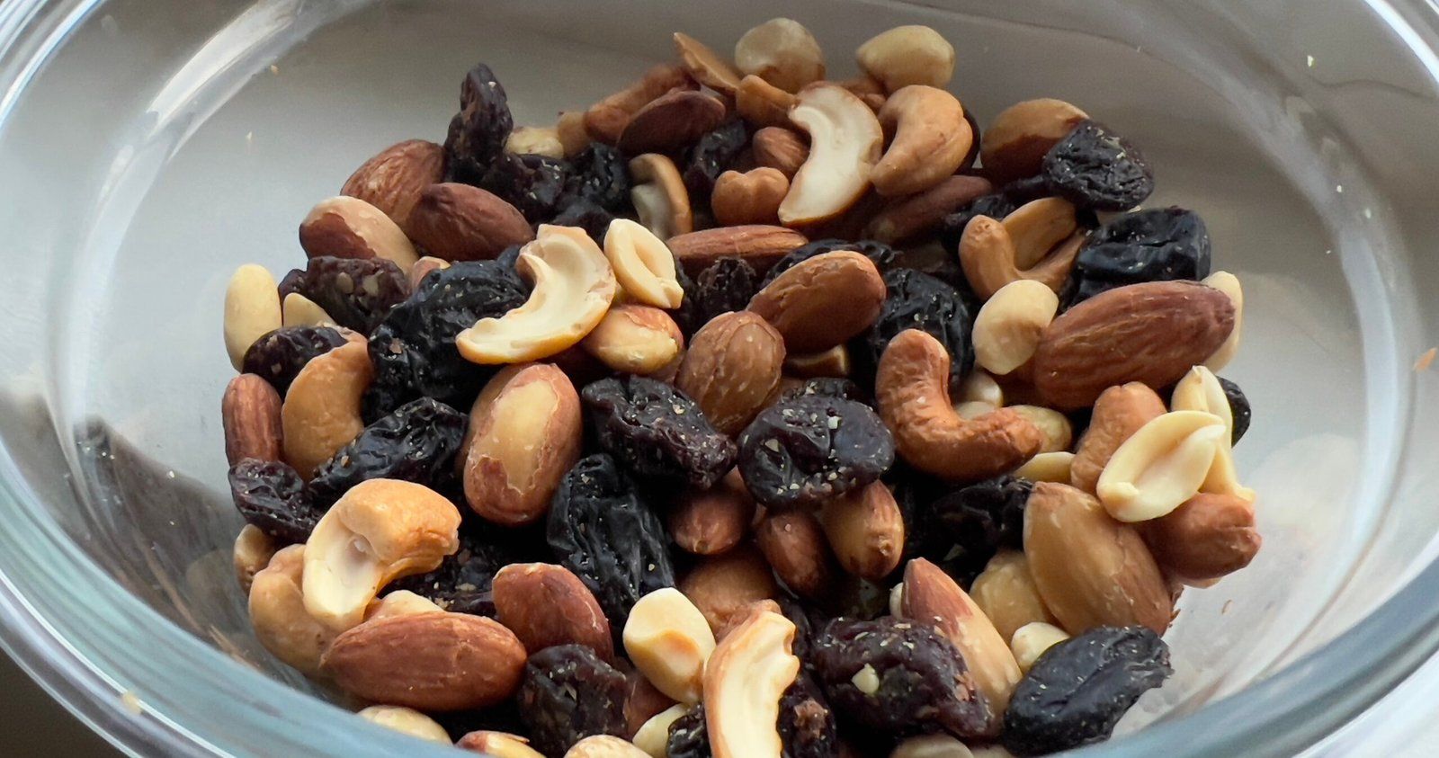 Bowl of trail mix with almonds, cashews, peanuts and raisins